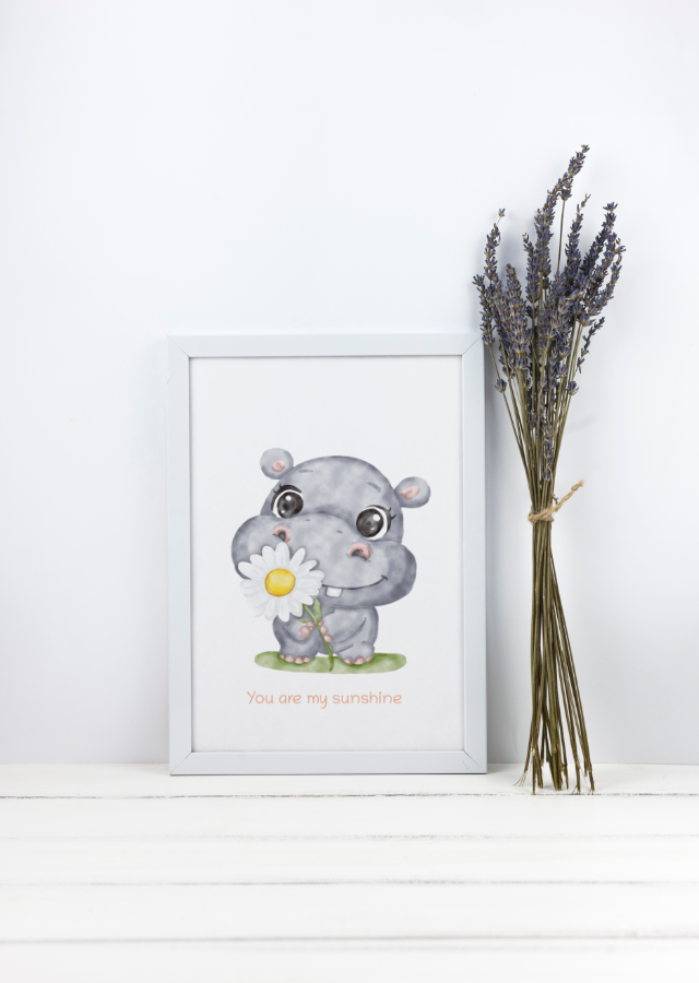 Framed illustration of a hippo holding a flower with text, next to a bundle of lavender on a white surface.